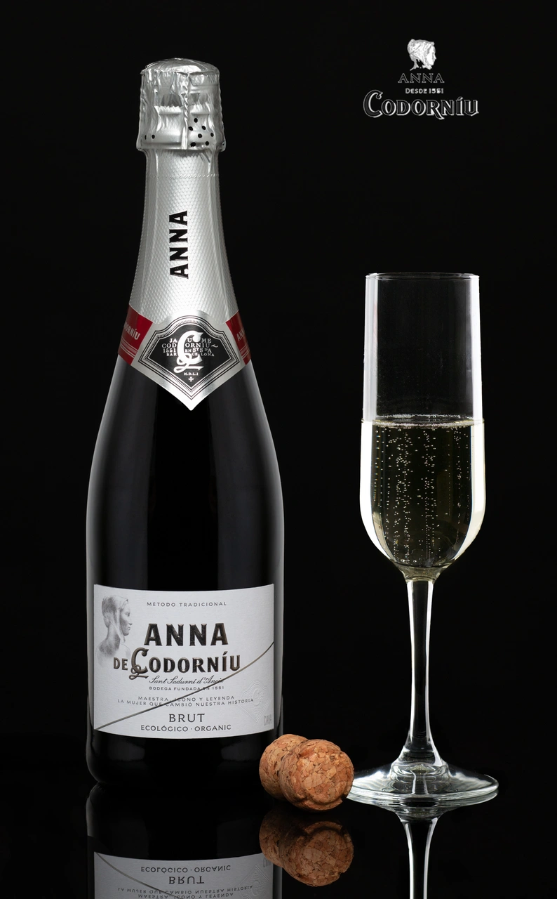 Ampolla de cava Anna de Codorníu i copa sobre un fons negre.