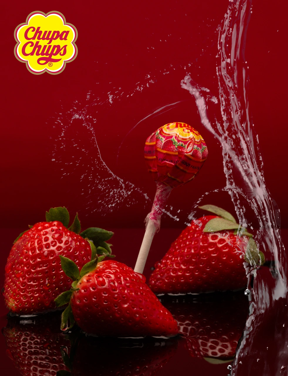 Composició amb una piruleta Chupa Chups, maduixes i aigua.